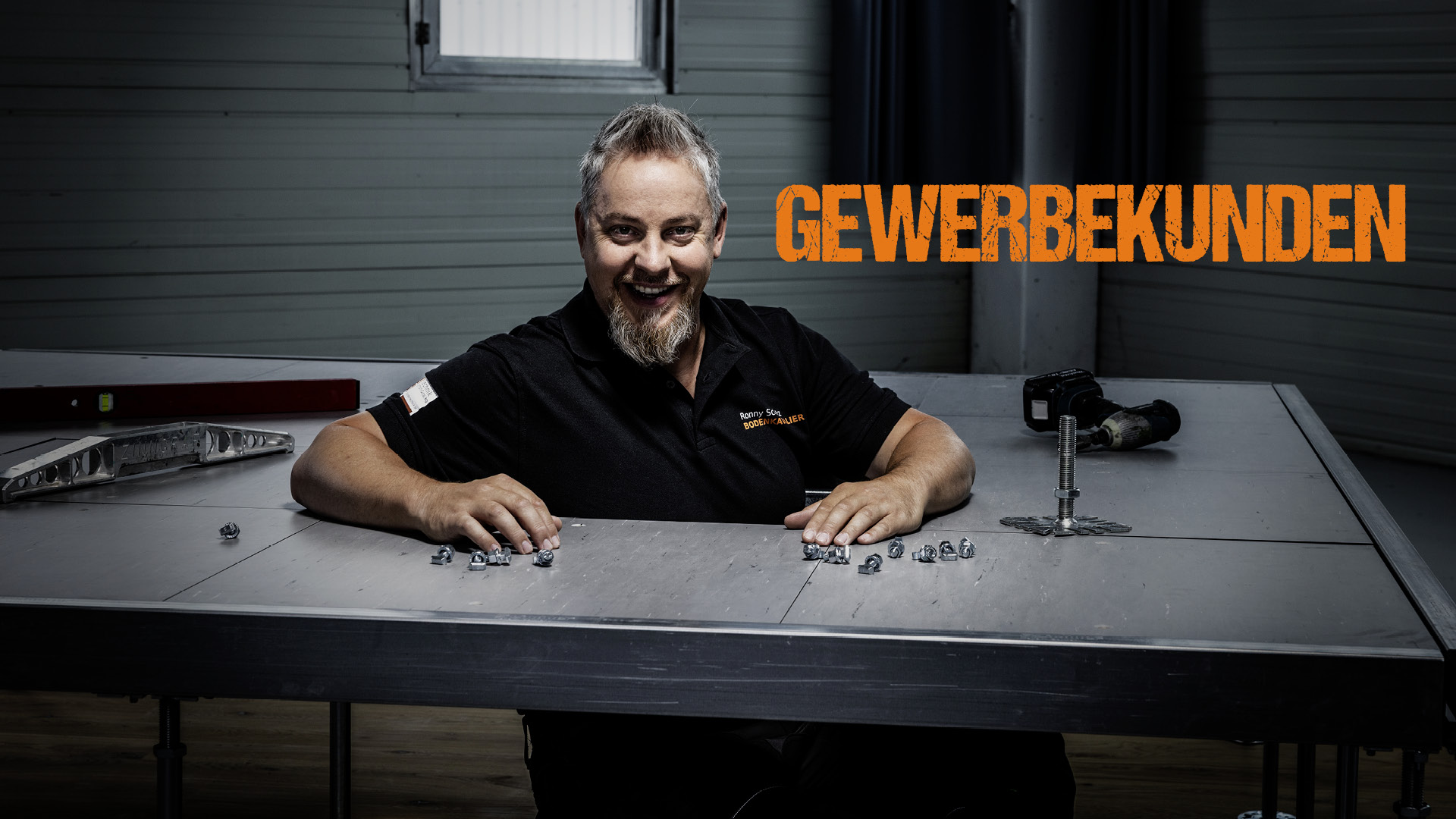 Ronny Schulz von RS Bodentechnik, der Bodenkavalier schaut aus einer Öffnung eines Doppelbodens. Gewerbekunden benutzen oft Doppelböden.