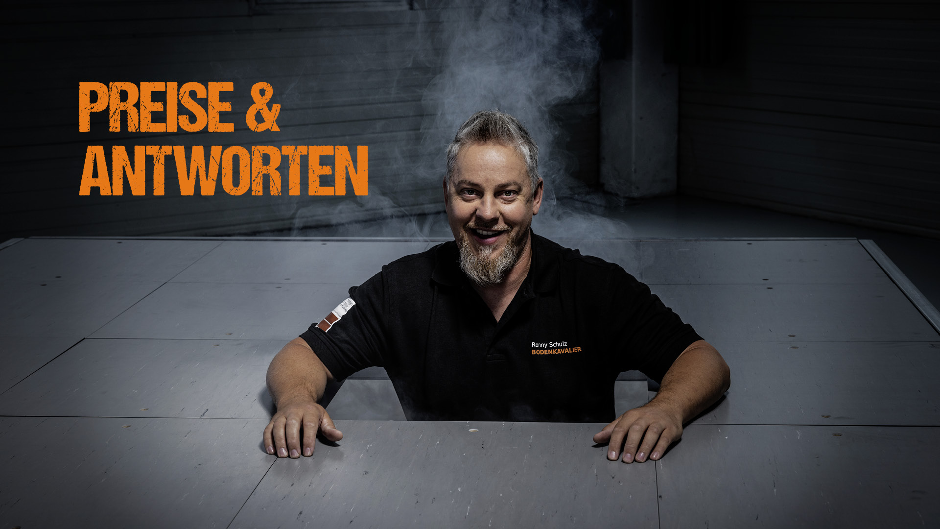 Ronny Schulz von RS Bodentechnik, der Bodenkavalier schaut aus der Öffnung eines Doppelbodens. Leichter Nebel steigt hinter ihm auf.